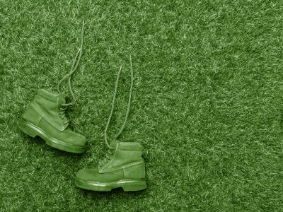 Kids fashion green boots on green grass background. The concept of the coming winter, selling shoes for children.